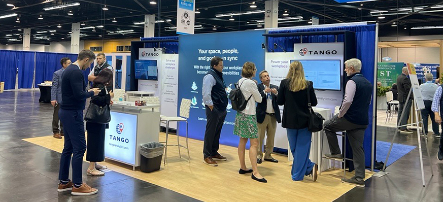 Trade show booth with people discussing software solutions.