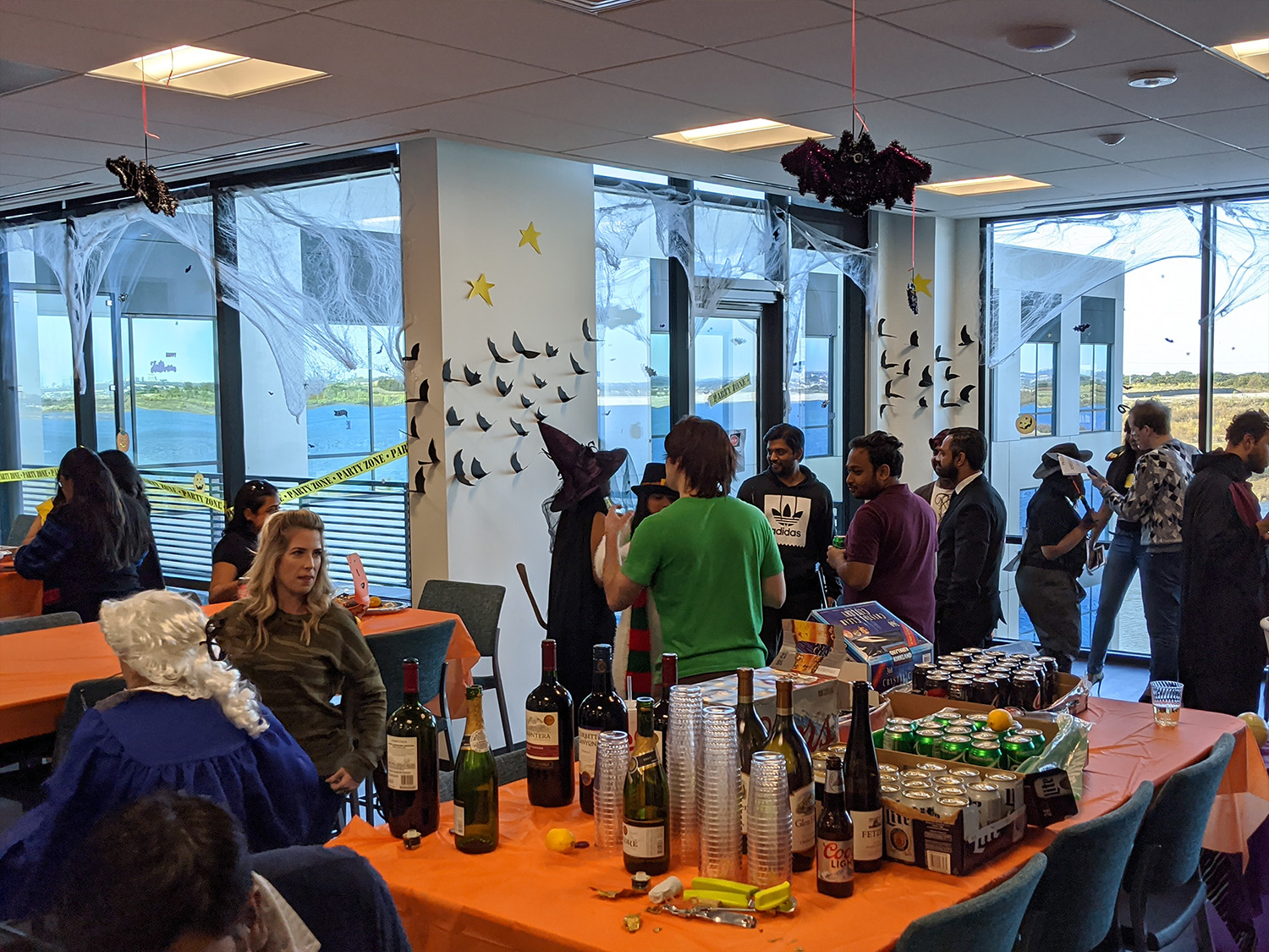 People at Halloween-themed office party with decorations.