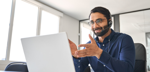 Man in headset video conferencing on laptop