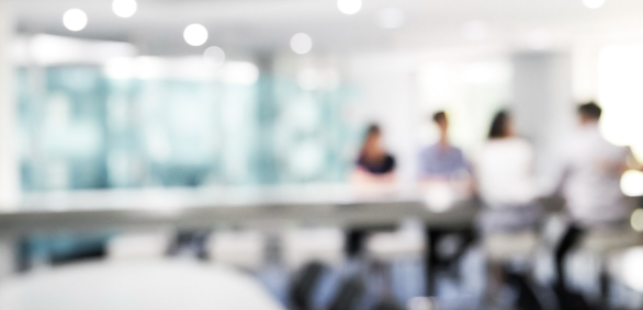 Blurred office meeting, people at table.