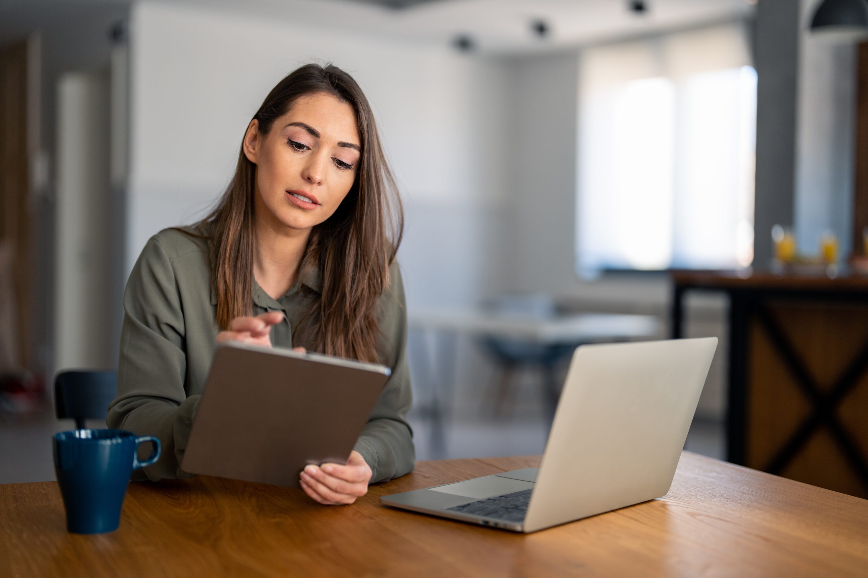 young,confident,successful,businesswoman,using,laptop,and,digital,tablet,,focused