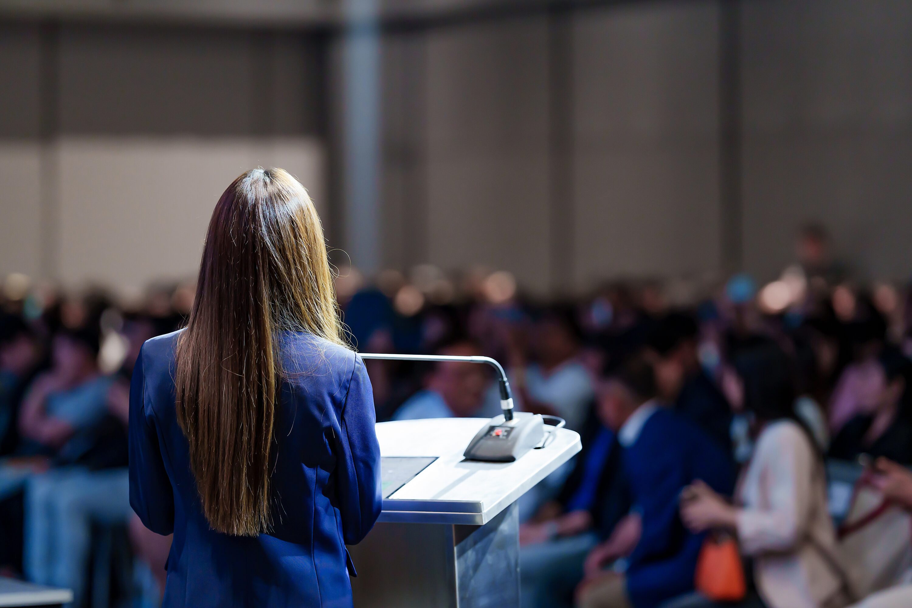 rear,view,of,woman,speaker,giving,an,inspiring,talk,or