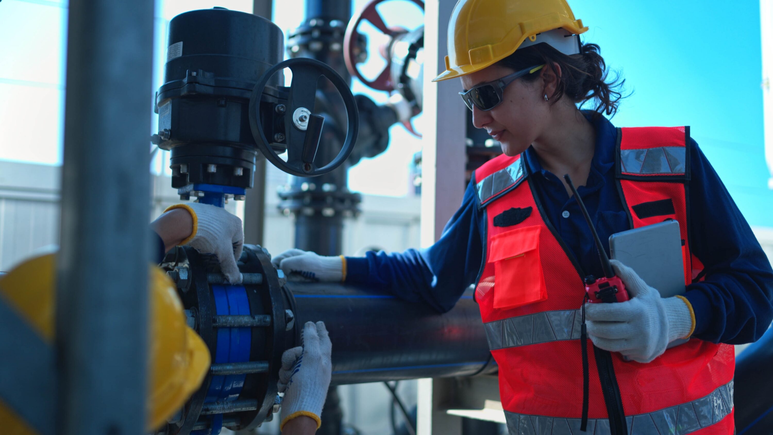 female,engineer,inspecting,industrial,pipeline,systems,while,communicating,via,walkie